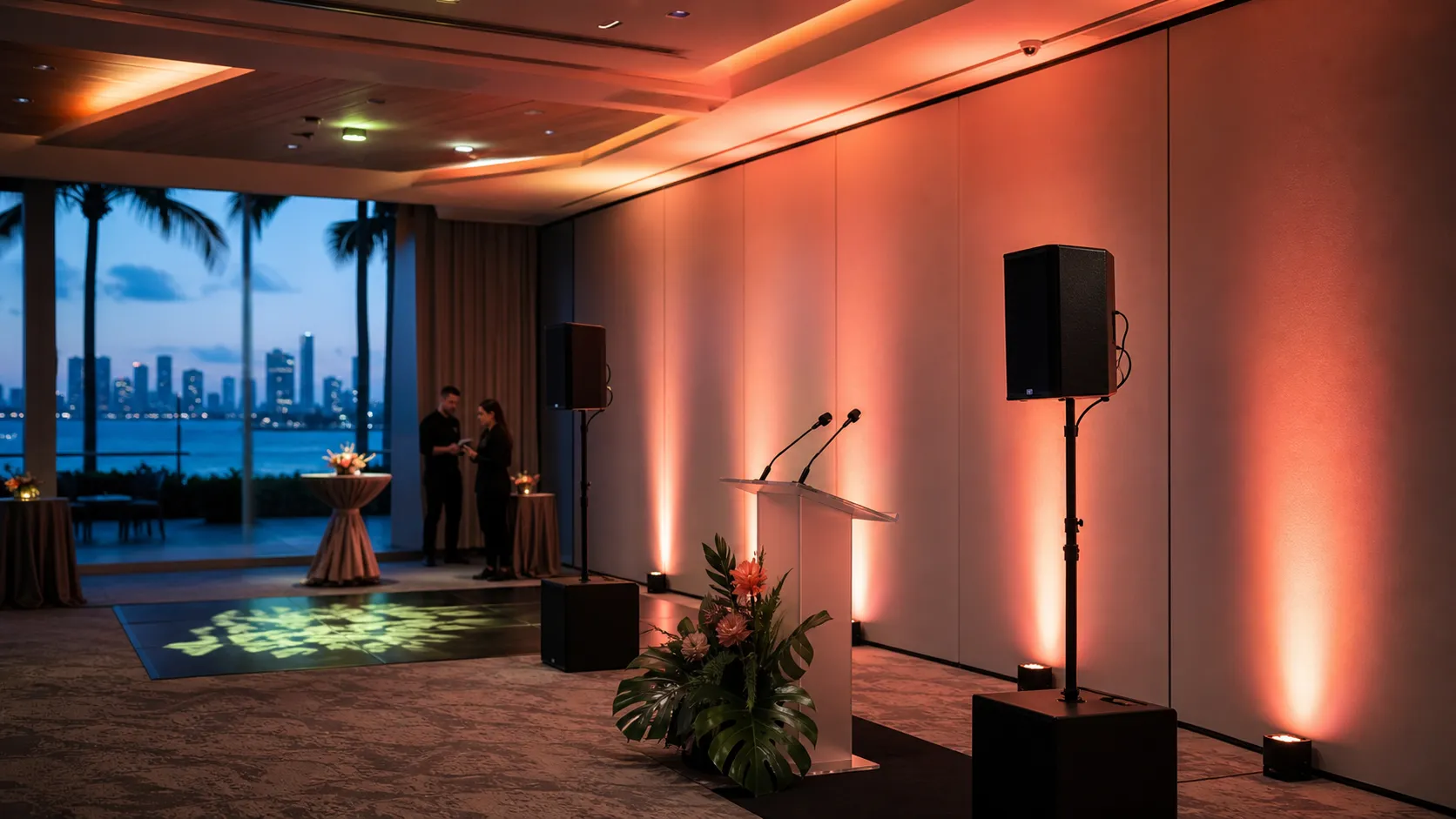 Lectern, wireless microphones, speakers, and warm uplighting in a waterfront event room